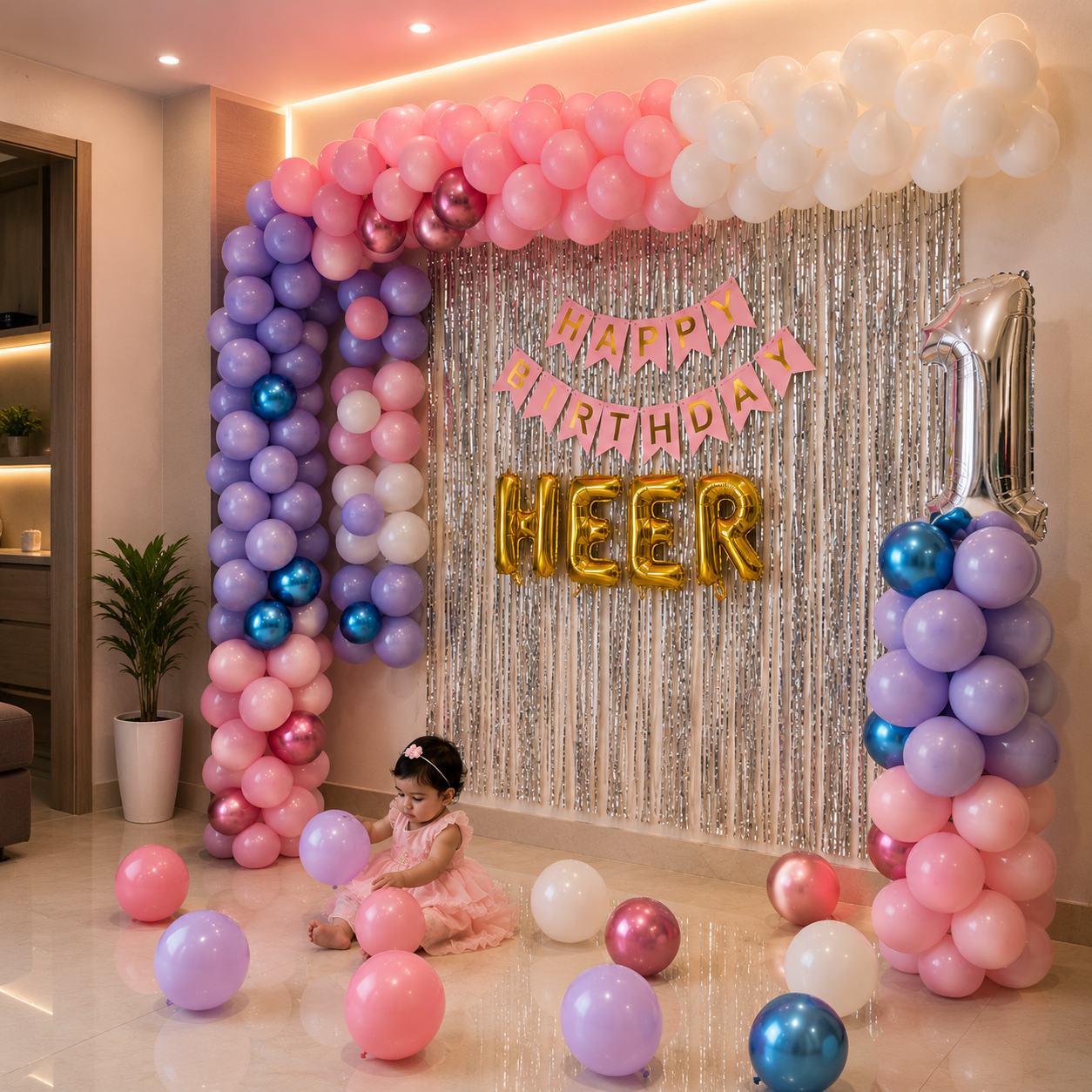 Child in a pink dress surrounded by balloons and 'Happy Birthday Meher' banner in a decorated room.