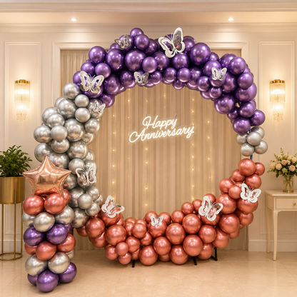 Balloon arch with purple, silver, and pink balloons in a room setting.