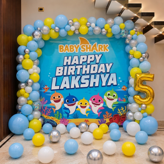 Birthday celebration setup with 'Baby Shark' theme, colorful balloons, and a 'Happy Birthday Lakshya' sign.