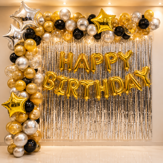 Birthday balloon arch with 'Happy Birthday' balloons against a silver tinsel curtain.