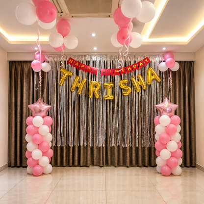 Decorative setup with balloons and 'Happy Birthday Thrisha' banner in a room.