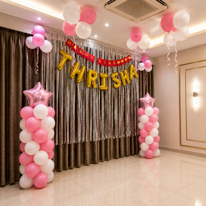 Decorated room with pink and white balloons, gold letter balloons spelling 'Happy Birthday Thrisa', and star-shaped balloons.