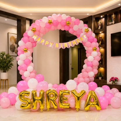 Balloon arch with 'Happy Birthday' and 'SHREYA' decorations in a room.
