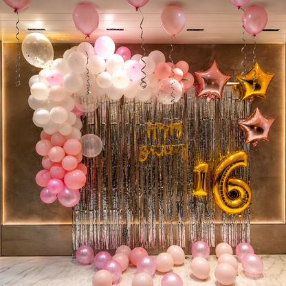 Decorative setup with balloons and 'Happy Birthday 16' banner on a metallic backdrop