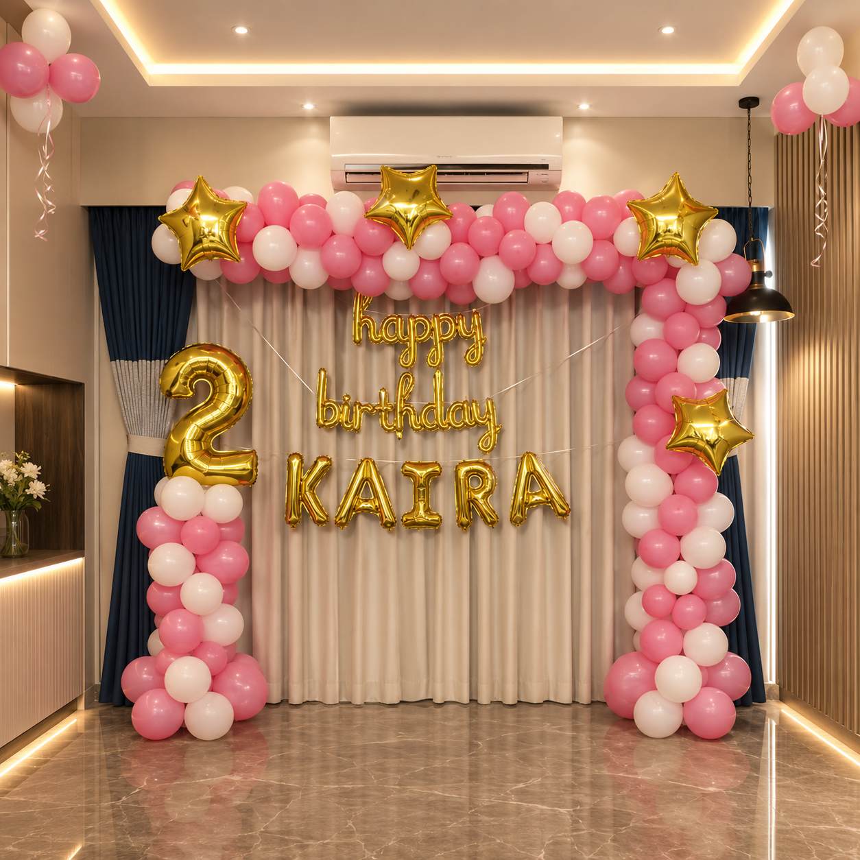Birthday balloon arch with 'Happy Birthday Kaira' text in a room.