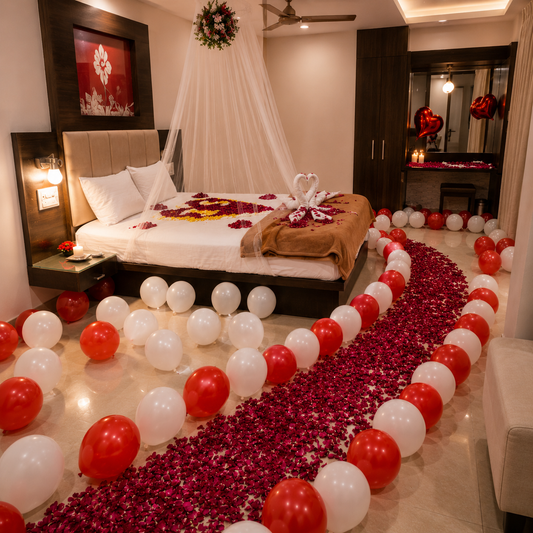 Decorated bedroom with balloons, rose petals, and a heart-shaped arrangement on the bed.