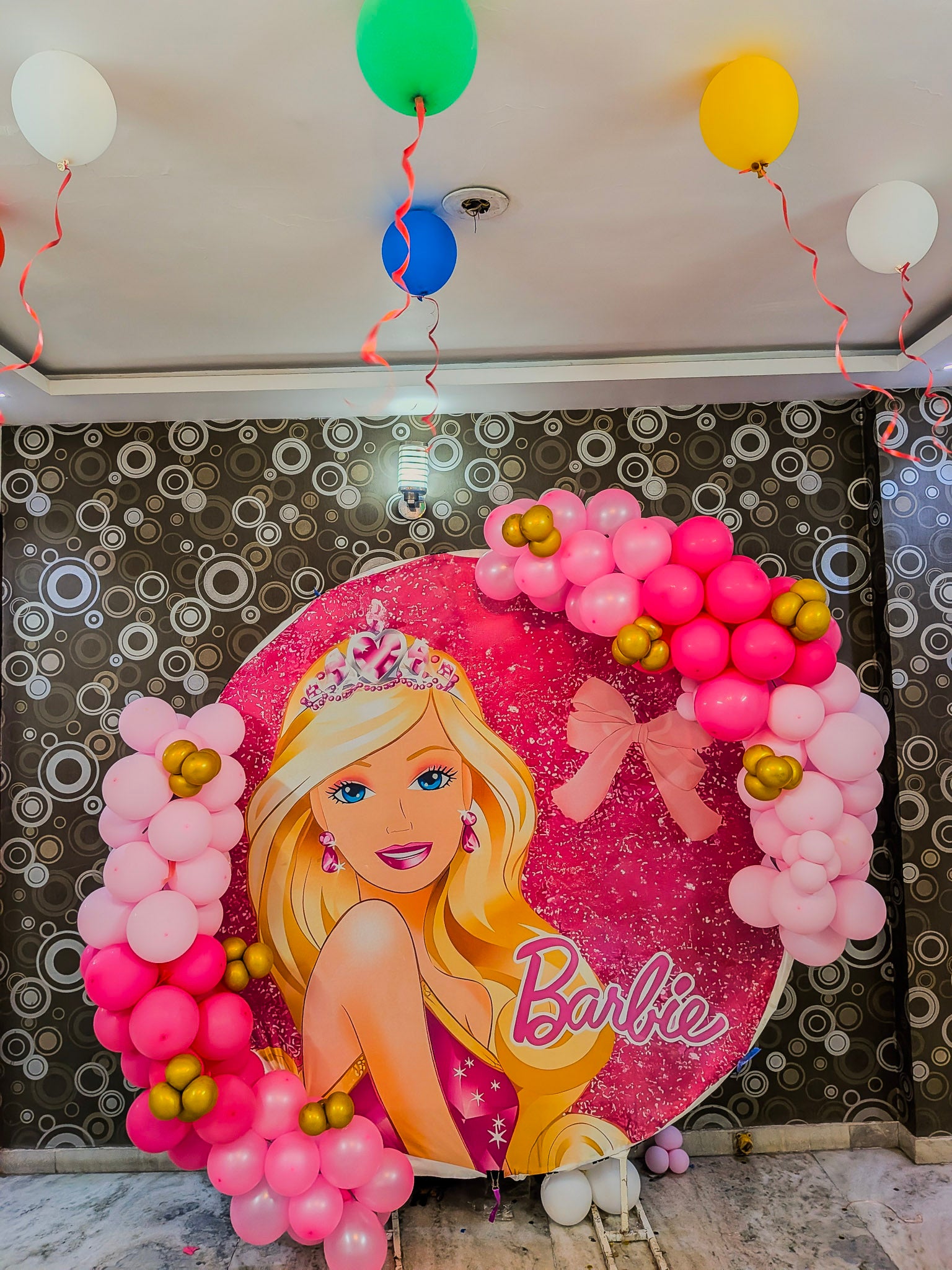 Barbie-themed balloon arch with colorful balloons in a decorated room.