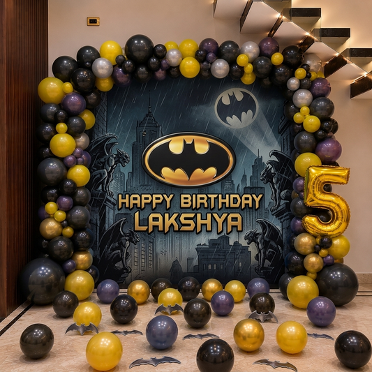 Batman-themed birthday decoration with balloons and 'Happy Birthday Lakshya' text.