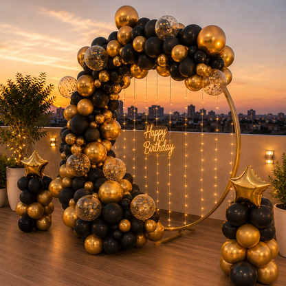 Balloon arch with 'Happy Birthday' sign on a rooftop at sunset