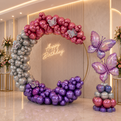 Balloon arch with 'Happy Birthday' sign and butterfly decorations in a decorated room.