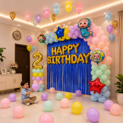 Child in a room decorated with colorful balloons and 'Happy Birthday' sign, celebrating a 2nd birthday.