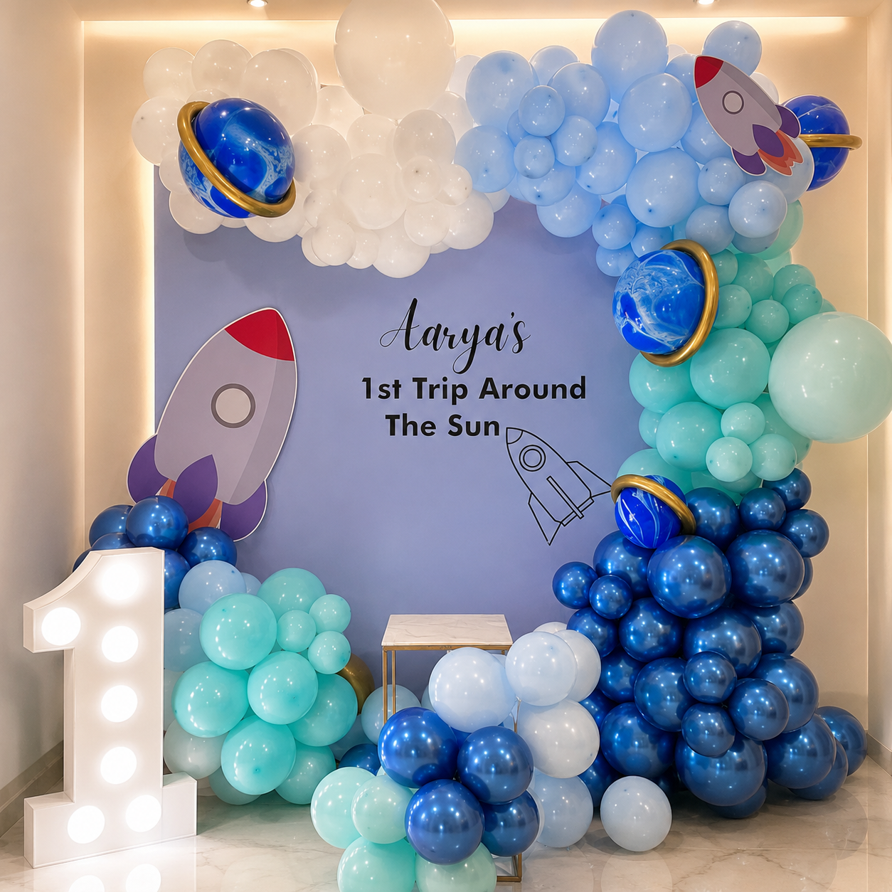 Space-themed balloon arch with planets and rockets, featuring a birthday message.