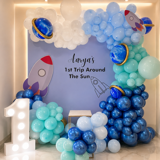 Space-themed balloon arch with planets and rockets, featuring a birthday message.