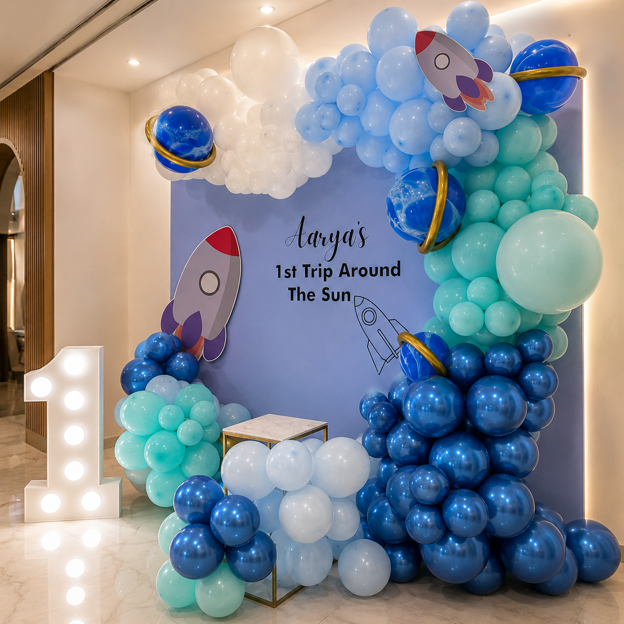 Balloon arch with space theme decorations and 'Arya's 1st Trip Around The Sun' text.