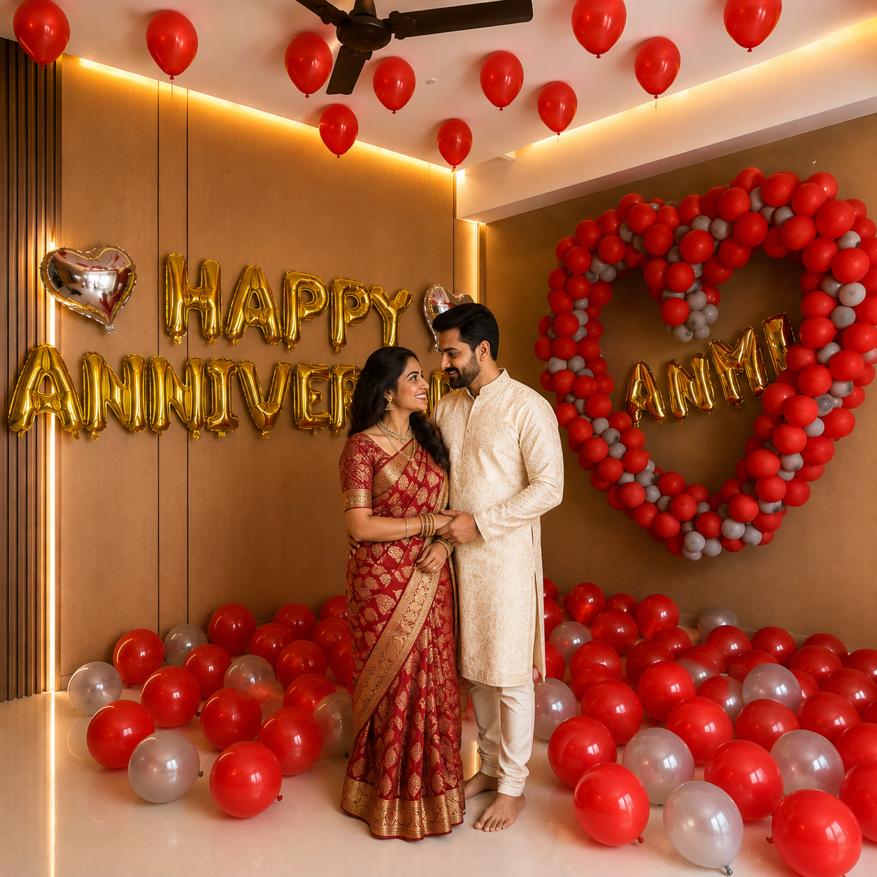 Couple in traditional attire standing in a decorated room with 'Happy Anniversary' balloons.