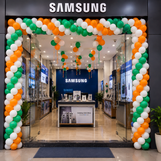 Samsung electronics store entrance decorated with a large balloon arch in green, white, and orange, with the Samsung logo displayed above the glass doors and on the blue interior back. 
Independence Day Balloon Decoration for Retail stores and Showroom 