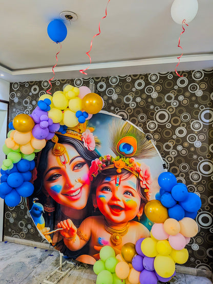 Decorative backdrop with colorful balloons and a portrait of a woman and child Krishna theme with face paint against a patterned wall.