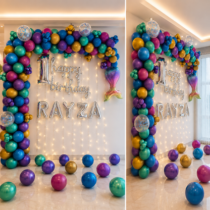 Colorful balloon arch with 'Happy Birthday Rayza' text in a room with string lights.