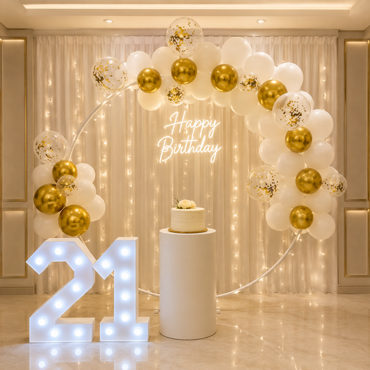 Birthday celebration setup with balloons, cake, and illuminated number 21 in a decorated room.