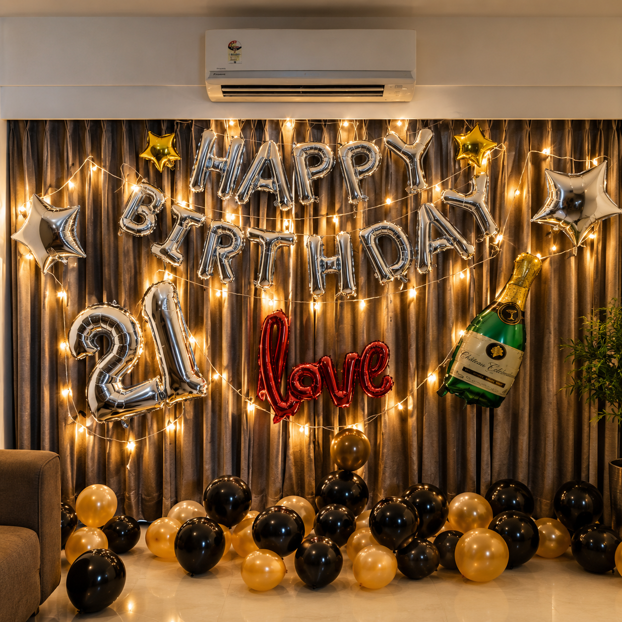 Birthday decoration with balloons, lights, and a bottle of champagne on a curtain backdrop.