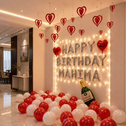 Decorated birthday room with balloons, champagne, and personalized 'Happy Birthday Mahima' sign.