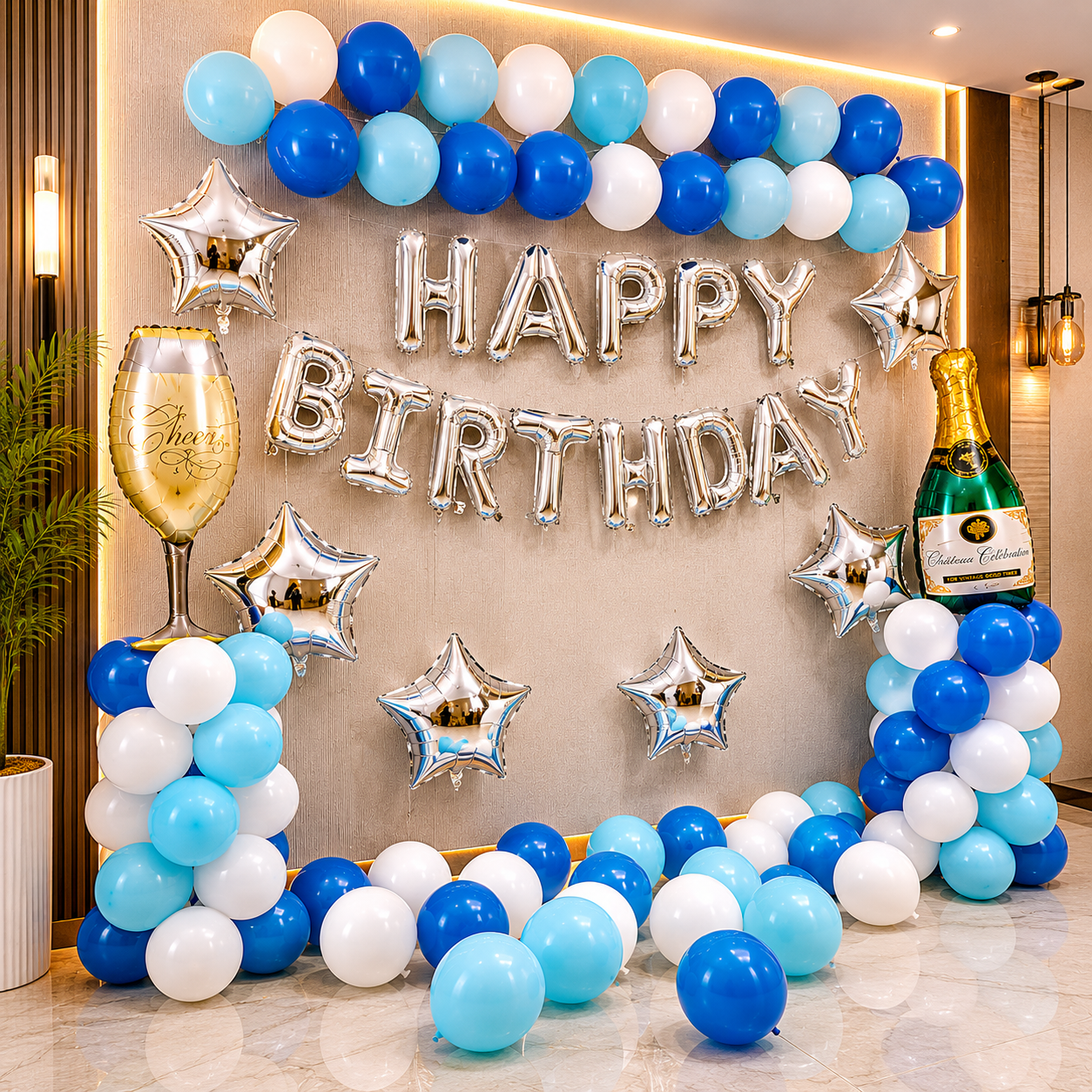 Birthday celebration setup with balloons, 'Happy Birthday' banner, and champagne bottle decorations.