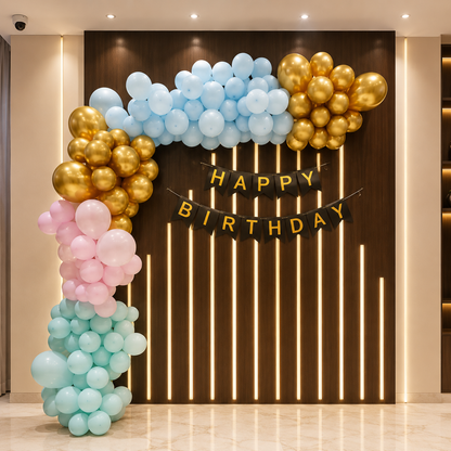 Balloon arch with 'Happy Birthday' banner against a dark wall with vertical lights