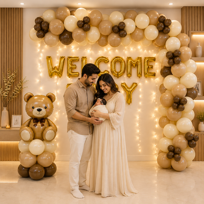 Newborn baby being held by parents under a 'Welcome Baby' balloon arch with decorative balloons and lights.
