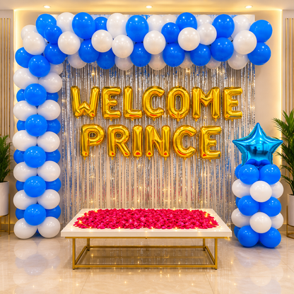 Decorative setup with balloons, 'Welcome Prince' balloons, and a table with red flowers in a well-lit room.