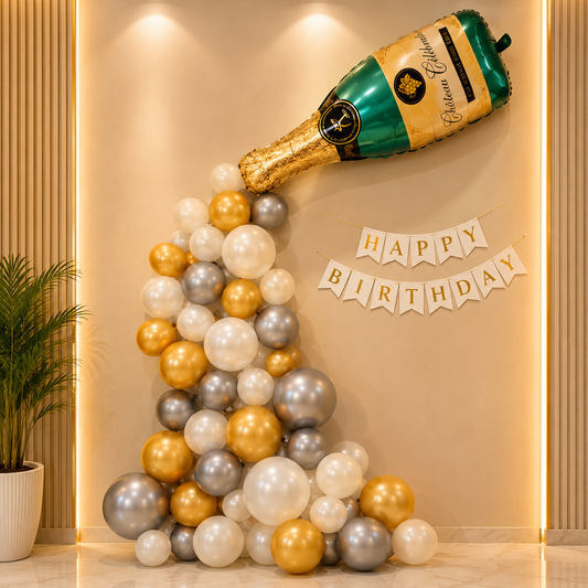Champagne bottle balloon and balloon arch with 'Happy Birthday' banner on a beige wall.