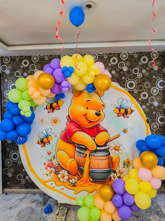 Decorative setup with Winnie the Pooh and balloons on a wall.